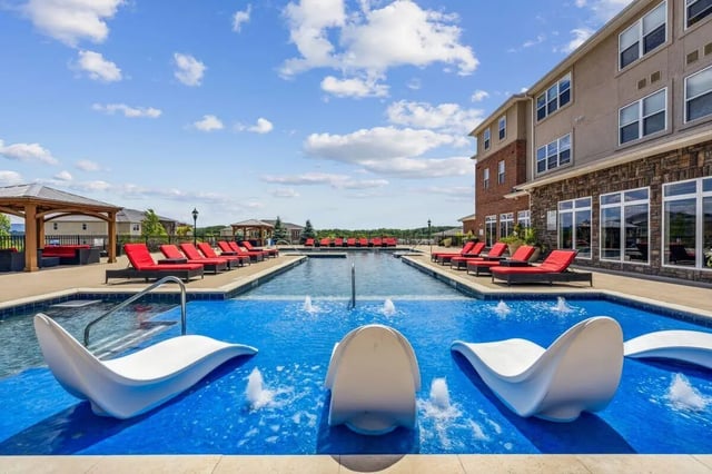 Pool with red loungers and modern white seating exterior at The View Apartments in State College Student Accommodation