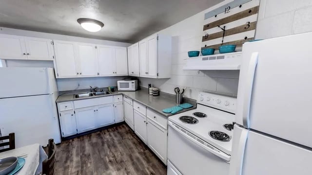White cabinets refrigerator oven microwave clock kitchen at Alpine Chalet in Rexburg Student Accommodation