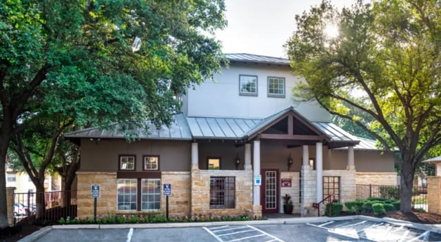 Building entrance with trees and parking lot exterior at The Cottages at Hillside Ranch in San Marcos Student Accommodation