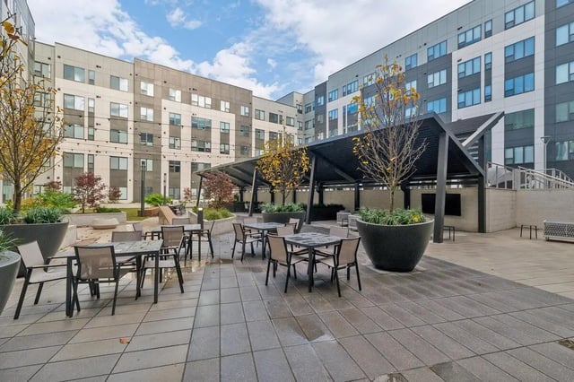 Tables and chairs under pergola outdoor lounge area at The Main on University in Fairfax Student Accommodation