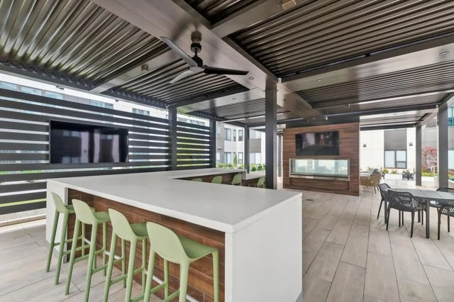Bar stools in front of a large counter with televisions. at The Main on University in Fairfax Student Accommodation