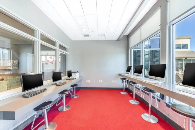 Computers and stools on red carpet study area at The Avenue at Orono in Orono Student Accommodation