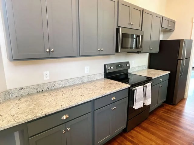 Gray cabinets microwave stove refrigerator granite countertop kitchen at College Corners on High in Farmville Student Accommodation