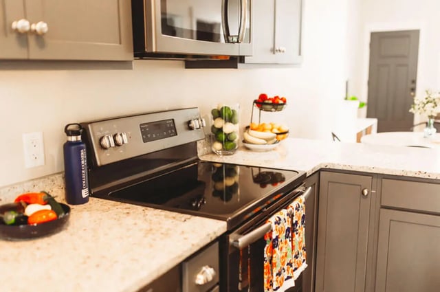 Gray cabinets microwave oven stove fruit bowl kitchen at College Corners on High in Farmville Student Accommodation