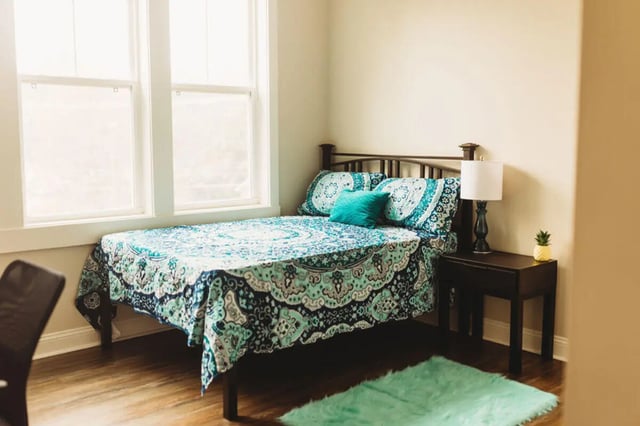 Bed with patterned bedding bedside table lamp pineapple Bedroom at College Corners on High in Farmville Student Accommodation