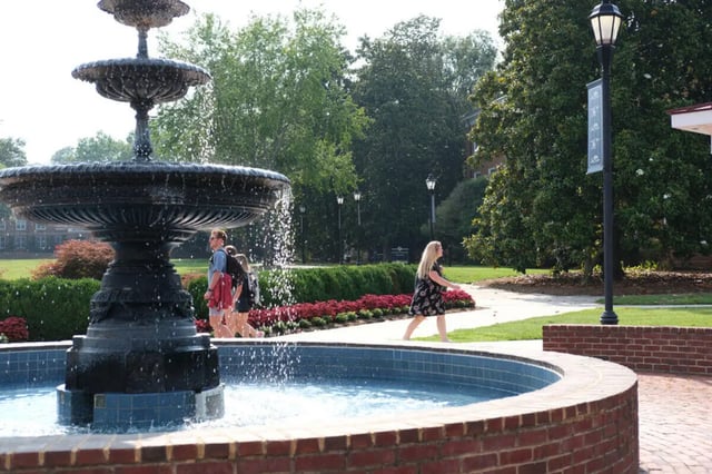 Fountain and people walking campus exterior at College Corners on High in Farmville Student Accommodation