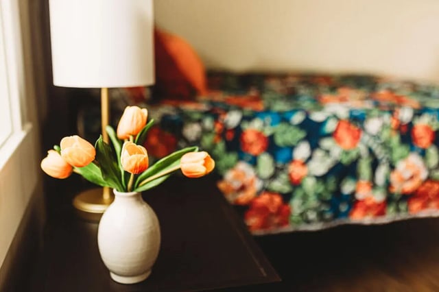 Tulips lamp bedside table floral bedspread bedroom at College Corners on High in Farmville Student Accommodation