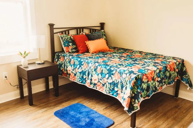 Floral bed bedside table lamp blue rug bedroom at College Corners on High in Farmville Student Accommodation