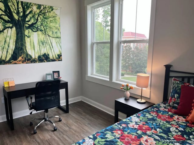 Desk chair lamp and floral bed linens bedroom at College Corners on High in Farmville Student Accommodation