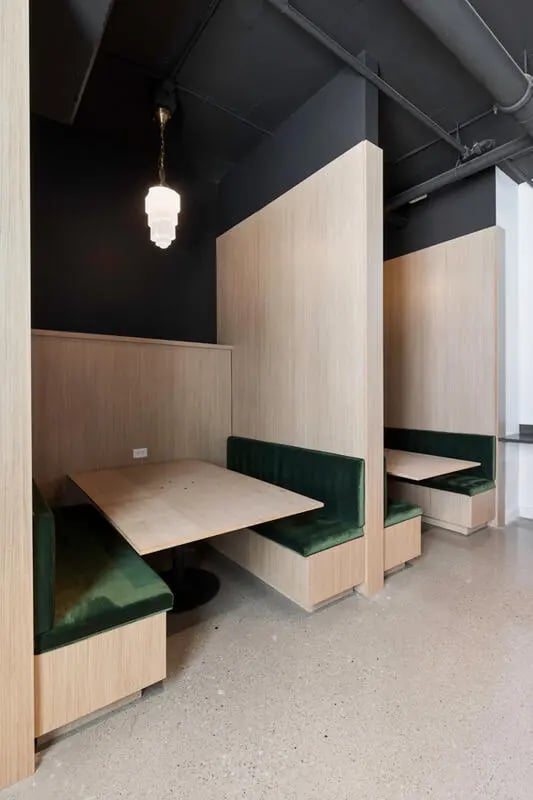 Booth seating with tables and green cushions common area at Atmosphere Lincoln in Lincoln Student Accommodation