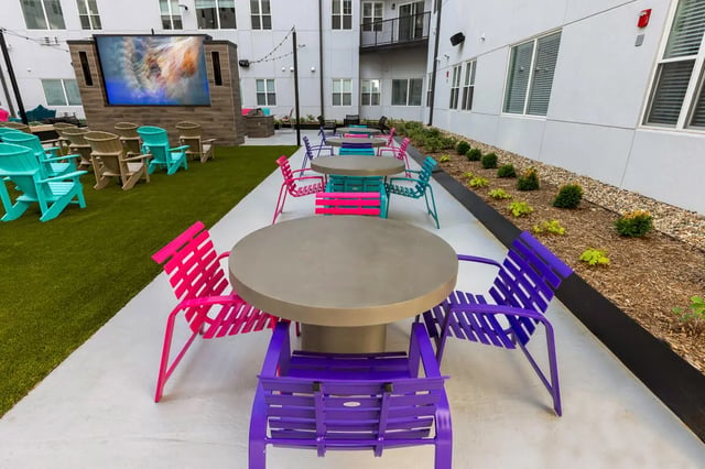 Colorful chairs tables large screen outdoor living area at Atmosphere Lincoln in Lincoln Student Accommodation