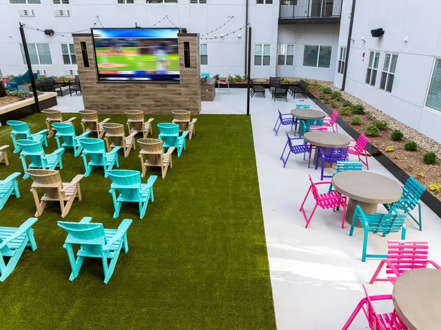 Outdoor movie screen with colorful chairs and tables outdoor area at Atmosphere Lincoln in Lincoln Student Accommodation