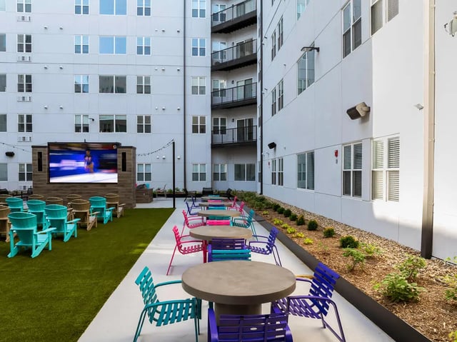 Outdoor courtyard with tables chairs and large screen at Atmosphere Lincoln in Lincoln Student Accommodation