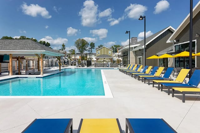Pool lounge chairs yellow umbrellas covered area exterior at University Trails Apartments in Ann Arbor Student Accommodation