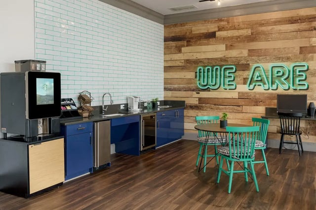 Coffee machine sink chairs table and neon sign communal area at The Summit at Coates Run in Athens Student Accommodation