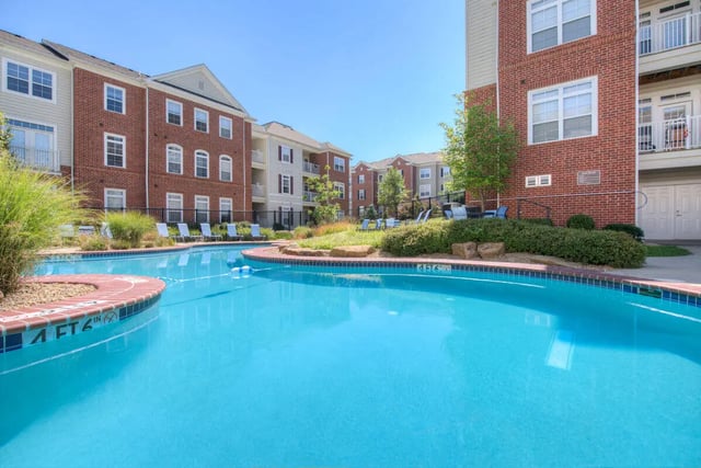 Pool chairs apartment buildings and green landscaping exterior at The Summit at Coates Run in Athens Student Accommodation