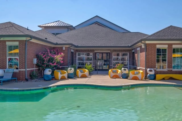 Pool chairs building windows yellow bench exterior at The Rendezvous Apartments in Edmond Student Accommodation