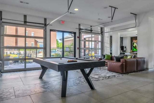 Pool table with balls and leather sofas Living room at The Rendezvous Apartments in Edmond Student Accommodation