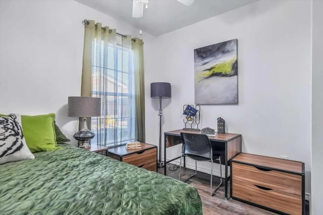 Bed with green quilt desk chair and artwork bedroom at The Rendezvous Apartments in Edmond Student Accommodation