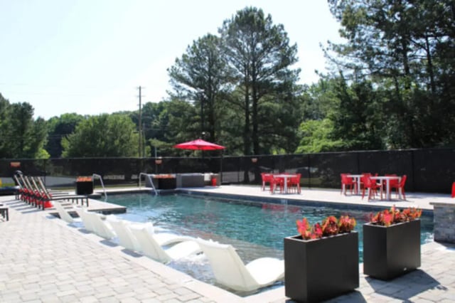 Pool with lounge chairs and red tables exterior at Hillside Commons in Tuscaloosa Student Accommodation