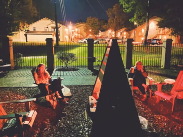 Two people sit in Adirondack chairs exterior at Hillside Commons in Tuscaloosa Student Accommodation
