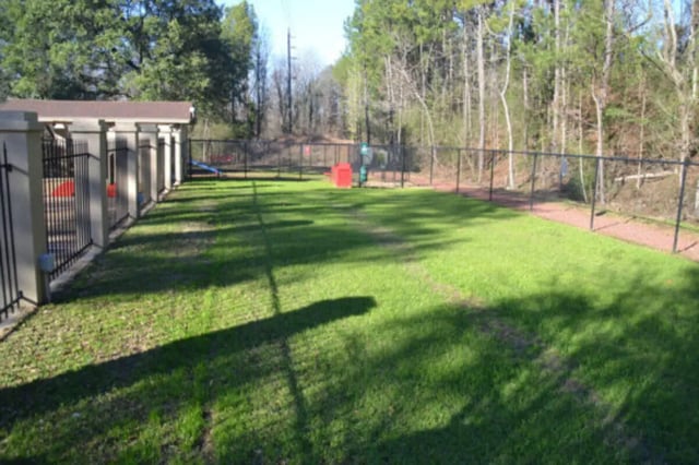 Fenced outdoor pet relief area with grass and play structures exterior at Hillside Commons in Tuscaloosa Student Accommodation