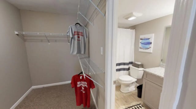 Closet with shirts and adjacent bathroom at Hillside Commons in Tuscaloosa Student Accommodation