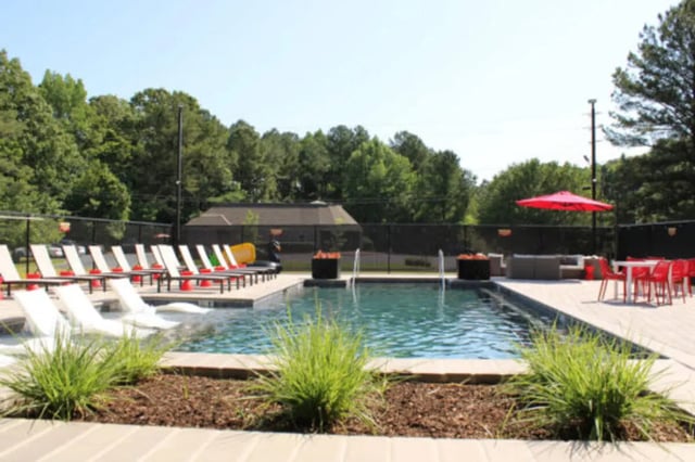 Pool with lounge chairs and outdoor dining area at Hillside Commons in Tuscaloosa Student Accommodation