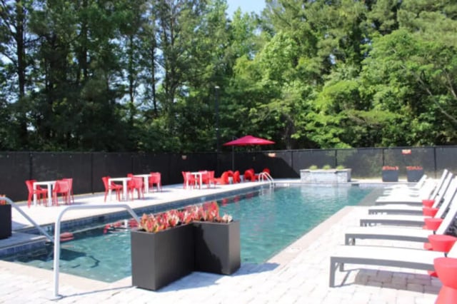 Pool with lounge chairs tables and red chairs exterior at Hillside Commons in Tuscaloosa Student Accommodation