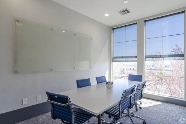 Conference table with blue chairs glass whiteboard large windows meeting room at The Republic in Reno Student Accommodation