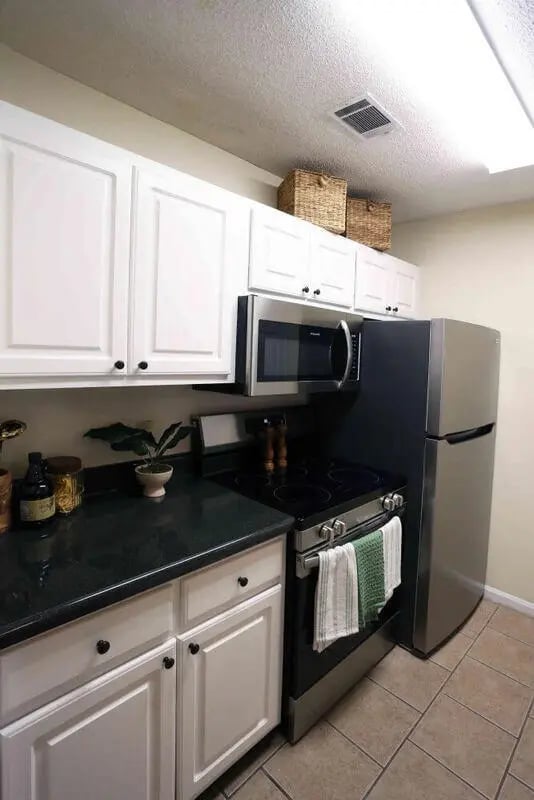 White cabinets black stove microwave refrigerator kitchen at Market 100 in Statesboro Student Accommodation