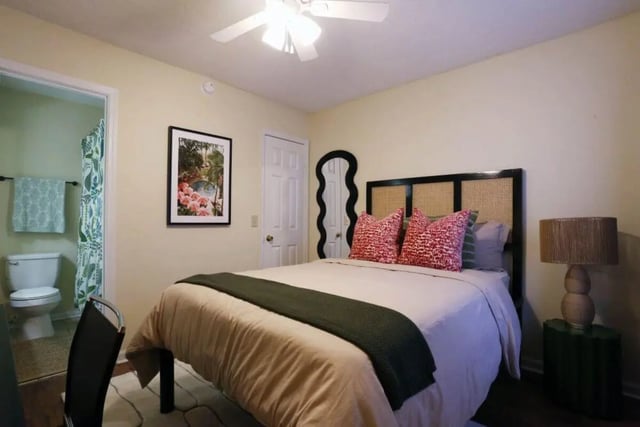 Bed with patterned pillows bathroom visible bedroom at Market 100 in Statesboro Student Accommodation