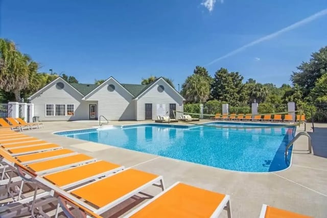 Swimming pool with orange loungers and building exterior at Market 100 in Statesboro Student Accommodation