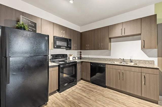 Black refrigerator stove microwave cabinets sink kitchen at Holleman Crossing in College Station Student Accommodation