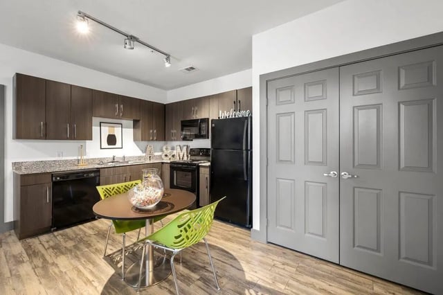 Kitchen with dining table and two green chairs Kitchen at Holleman Crossing in College Station Student Accommodation