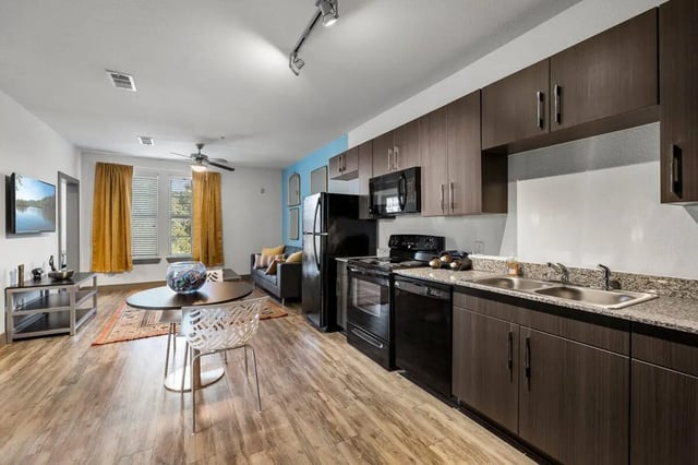 Kitchen with cabinets refrigerator stove and dining area Living area at Holleman Crossing in College Station Student Accommodation