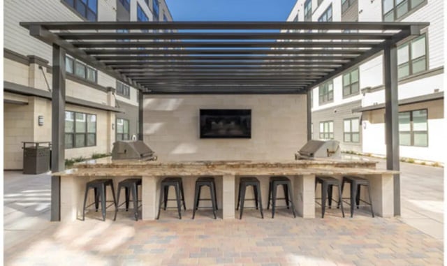 Outdoor kitchen with grills bar stools and TV area at The Carlton House in Lubbock Student Accommodation