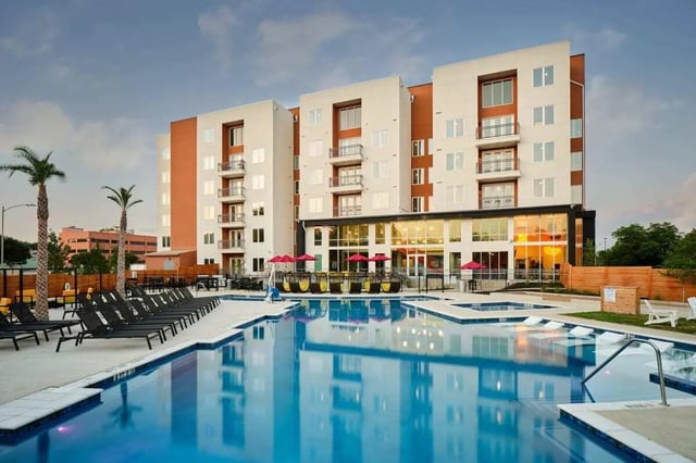 Pool and lounge chairs with modern apartment building exterior at The View on the Square in San Marcos Student Accommodation