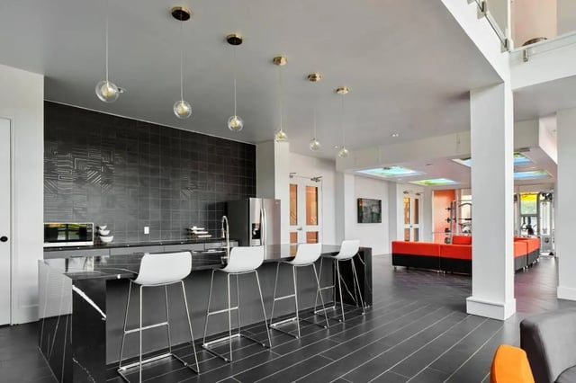 Modern kitchen island with stools and lounge area living room at The View on the Square in San Marcos Student Accommodation
