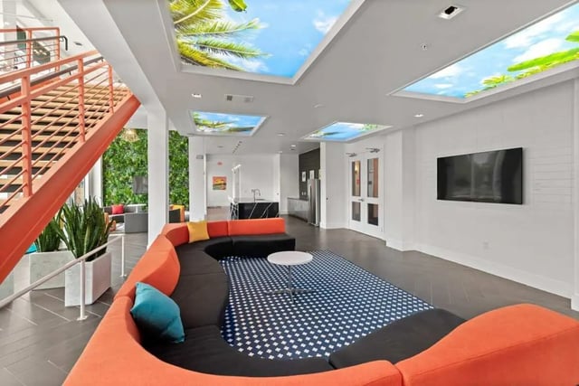 Orange sectional sofa blue rug flat screen living room at The View on the Square in San Marcos Student Accommodation
