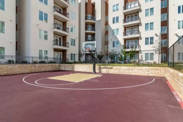 Basketball court with hoop and apartment building exterior playing area at The View on the Square in San Marcos Student Accommodation