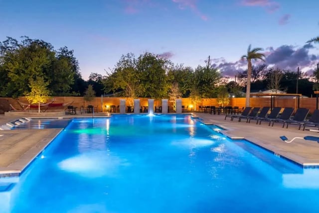Lit swimming pool with lounge chairs and tables pool area at The View on the Square in San Marcos Student Accommodation