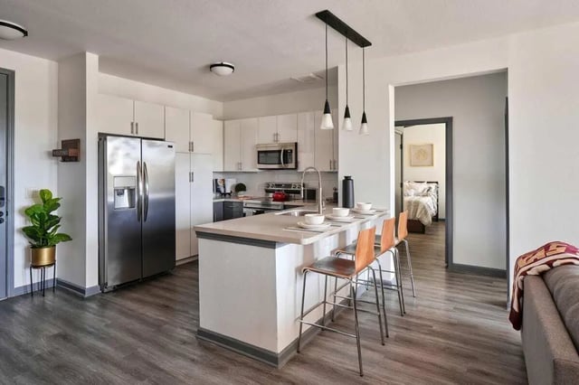 Kitchen island with bar stools and open bedroom view kitchen at The View on the Square in San Marcos Student Accommodation