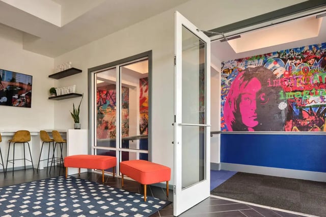 Orange ottomans graphic art wall stools and TV living room at The View on the Square in San Marcos Student Accommodation