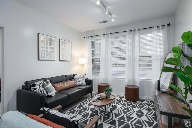 Black leather sofa patterned rug and ottomans living room at Paloma Kent in Kent Student Accommodation