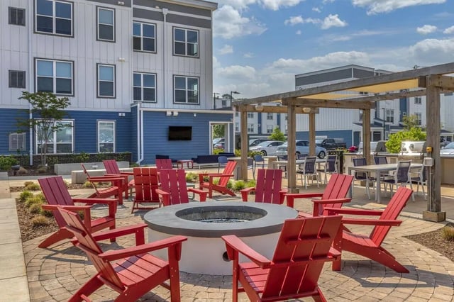 Red chairs surround fire pit outdoor communal area living room at Paloma Raleigh in Raleigh Student Accommodation