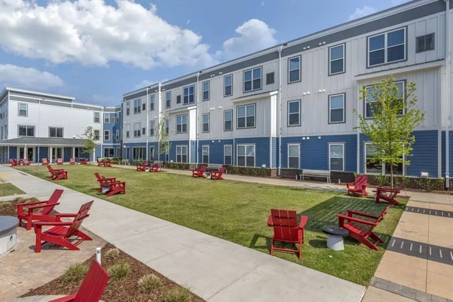 Red chairs on grassy courtyard exterior at Paloma Raleigh in Raleigh Student Accommodation