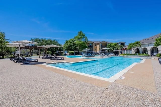 Resort style pool with lounge chairs and umbrellas swimming area exterior at University Trails College Station in College Station Student Accommodation