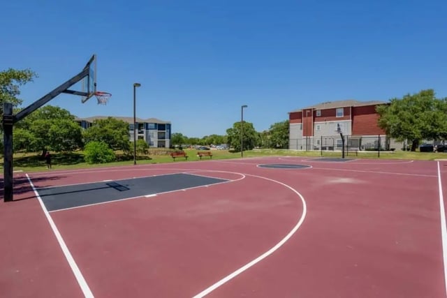 Basketball court with benches and apartment buildings exterior at University Trails College Station in College Station Student Accommodation