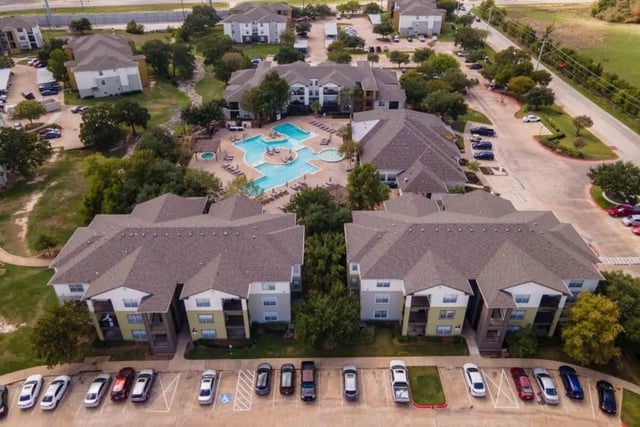 Apartment complex with swimming pool and parking lot exterior at University Trails College Station in College Station Student Accommodation